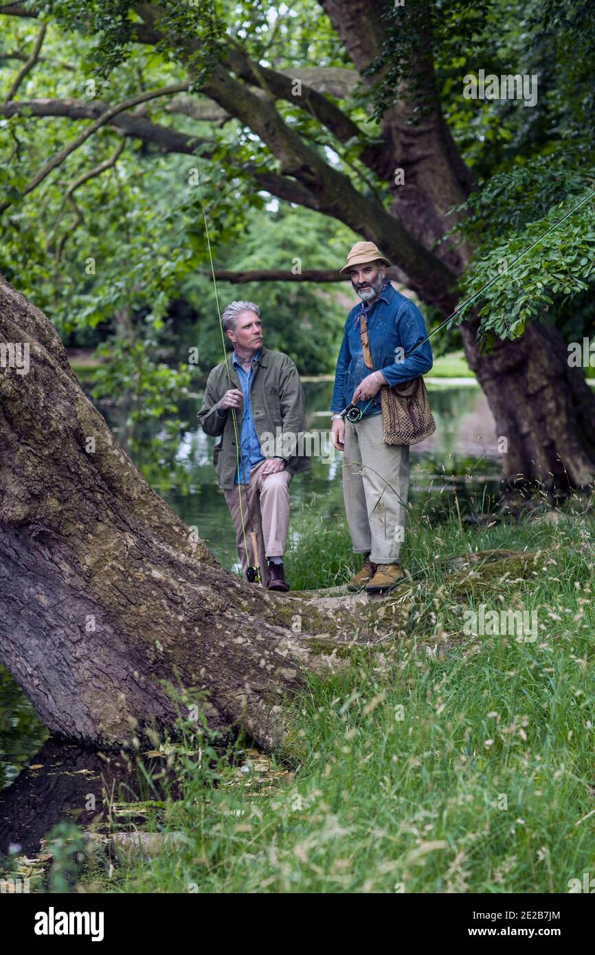 Deux hommes pêche à la mouche dans le lac entouré d'arbres Banque D'Images