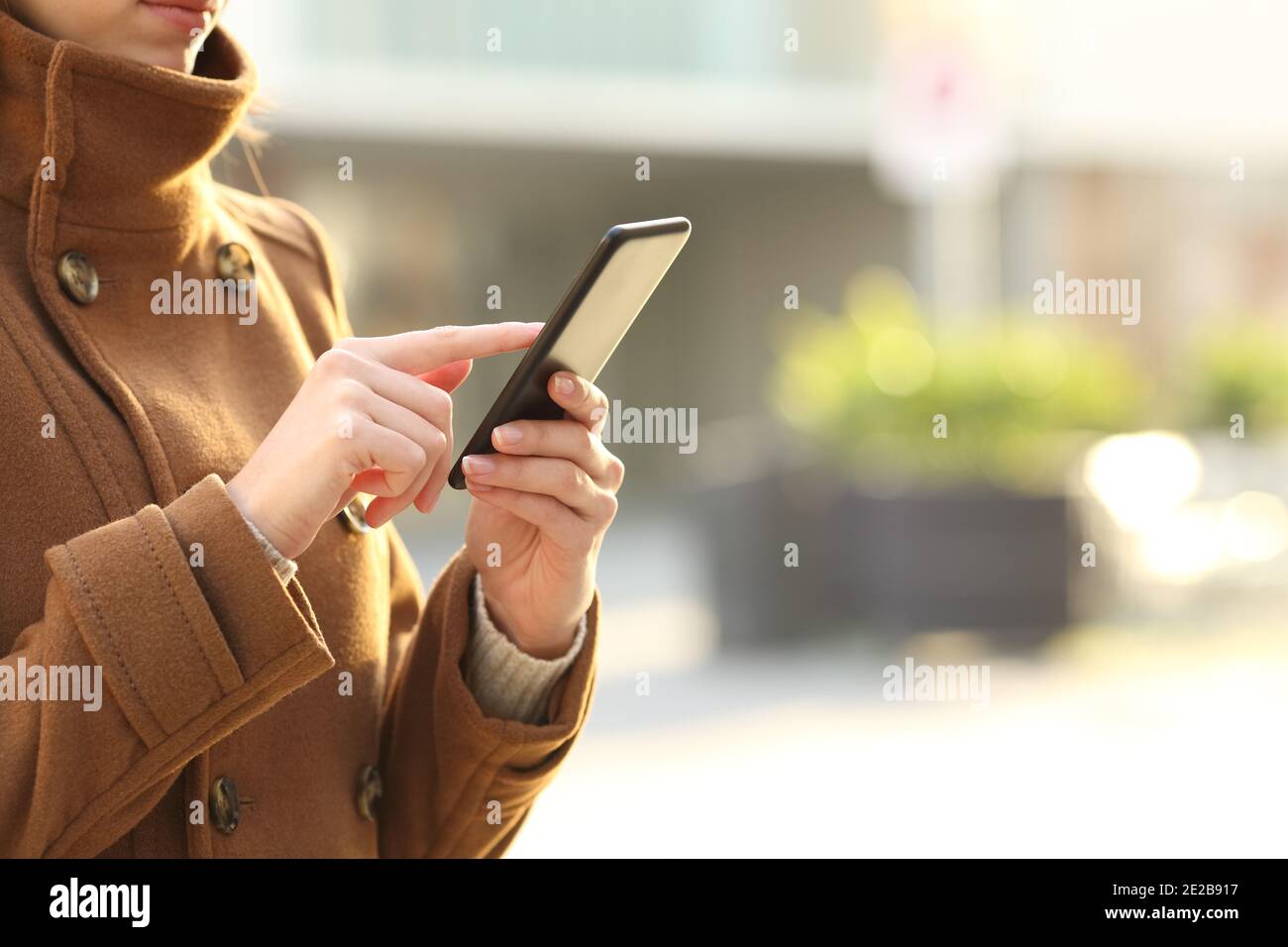 Gros plan des mains d'une femme en hiver à l'aide d'un smartphone marche dans la rue Banque D'Images