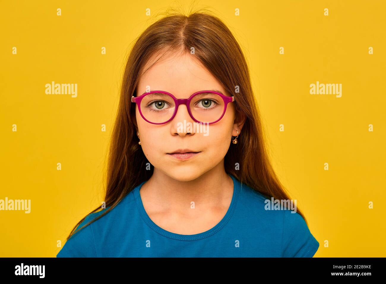 Petite fille avec lunettes isolées sur fond jaune. Correction de la vision pour les enfants Banque D'Images