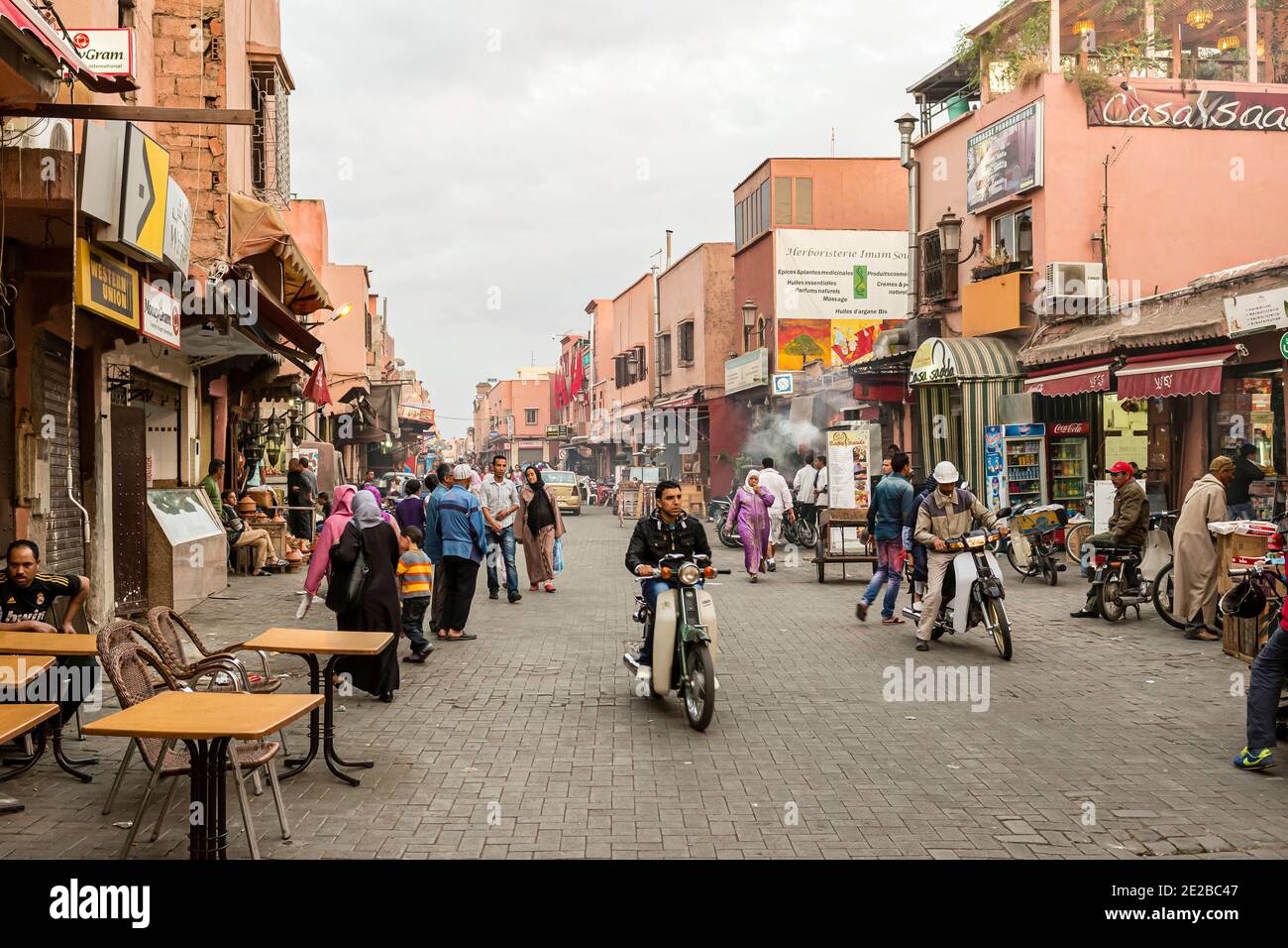 Une rue commerçante animée dans la Médina de Marrakech, avec des shoppers et motocyclistes, Maroc Banque D'Images