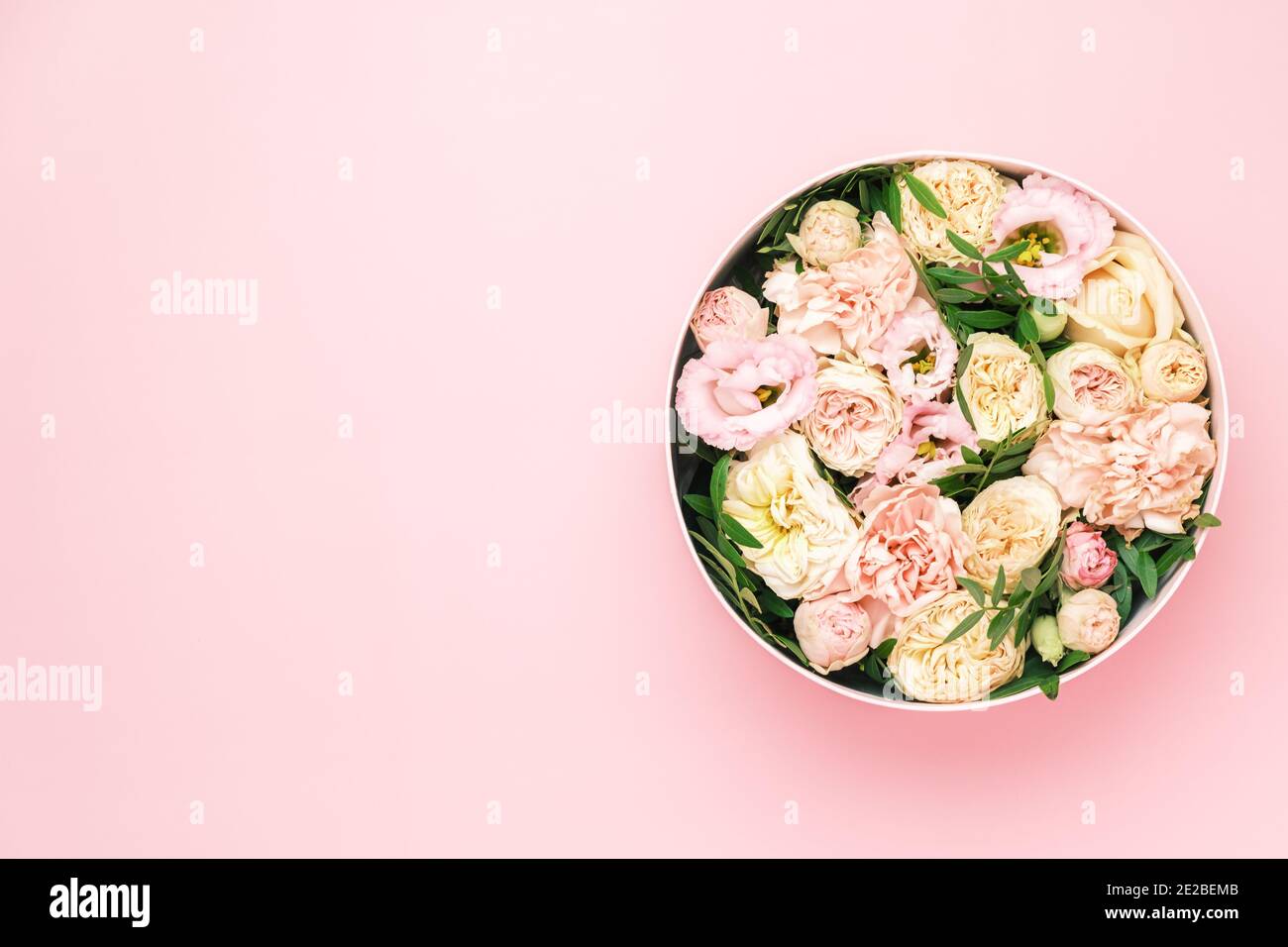 Une fleur élégante et délicate dans une boîte ronde à chapeau sur fond rose avec espace de copie. Boîte cadeau pour le 8 mars, Journée internationale de la femme Banque D'Images