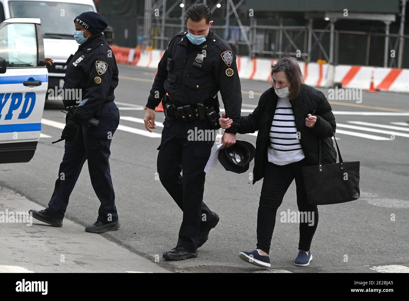 Un officier de NYPD aide une dame âgée aux portes du Centre de congrès Jacob K. Javits qui ouvre aujourd'hui un site de vaccination COVID-19 géré par l'État, New York, NY, le 13 janvier 2021. Autrefois utilisé comme hôpital de traitement sur le terrain du coronavirus en mars 2020 lors de la première vague d'infections à COVID-19, le centre Jacob Javits sera maintenant utilisé pour accélérer encore la distribution des vaccins à New York; L'État de New York est actuellement en phase 1B, avec une priorité de vaccination pour les travailleurs de la santé, les personnes âgées de 65 ans et plus, les premiers intervenants, les éducateurs et les travailleurs essentiels. (Photo par Anthony be Banque D'Images