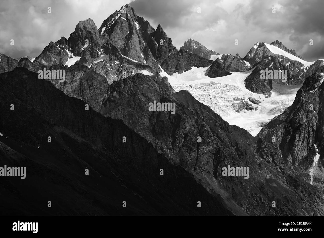 Hautes montagnes rocheuses avec glacier dans les nuages de tempête avant la pluie. Montagnes du Caucase. Géorgie, région de Svanetia en été. Emplacement distant. Noir et blanc Banque D'Images
