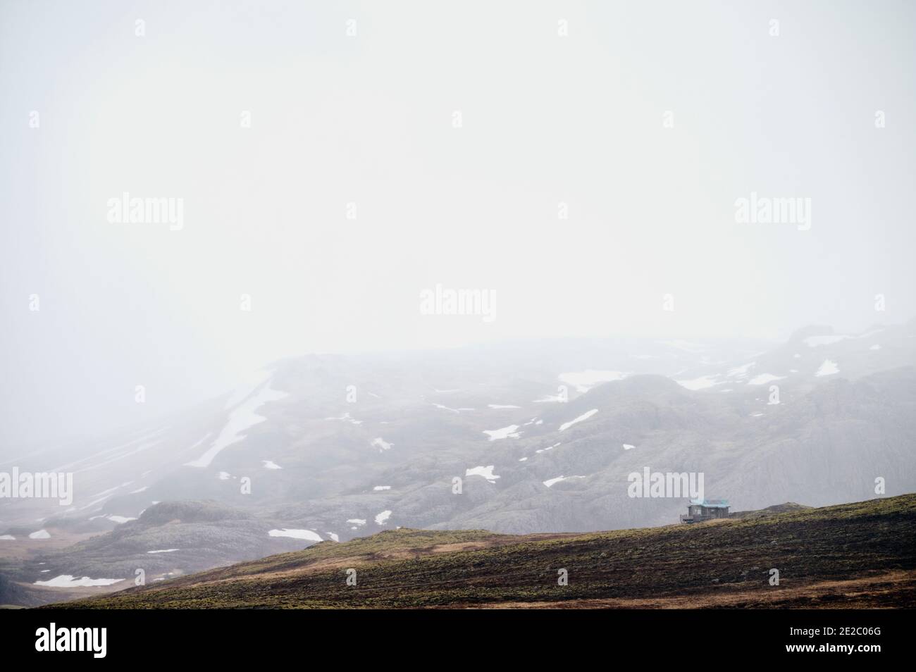 Cottage éloigné situé près des montagnes enneigées par temps froid sombre en hiver dans la nature Banque D'Images