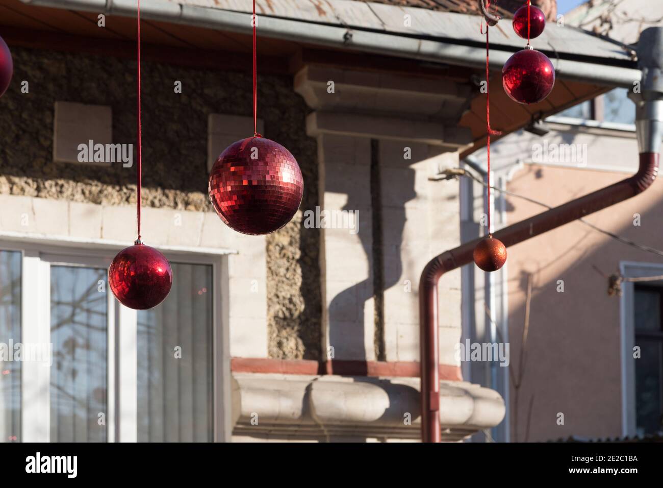 Détails de décoration de Noël dans les rues de la ville pour les vacances du nouvel an: Boules rouges et or sur un arbre sur le fond du bâtiment et garlan Banque D'Images