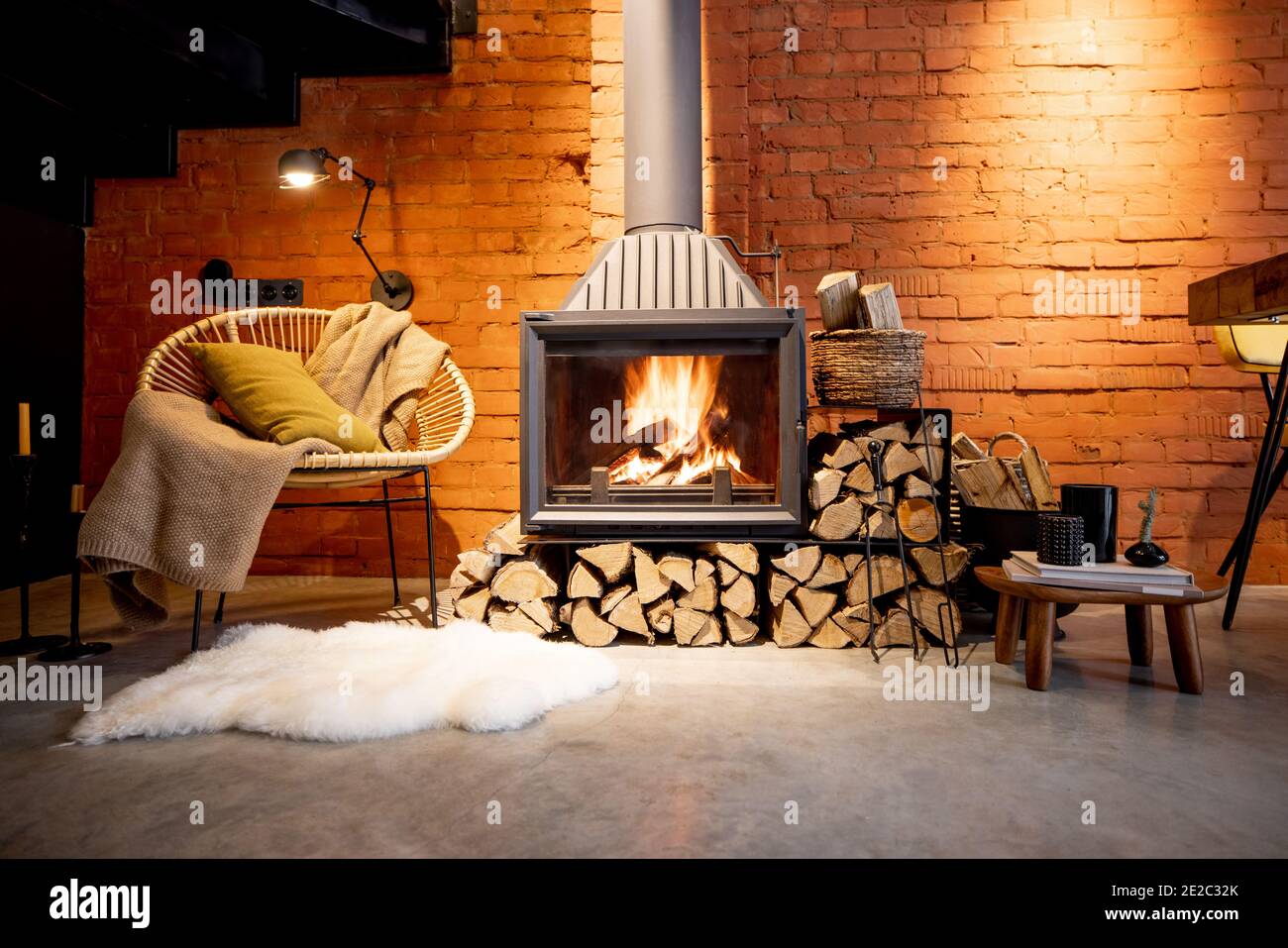 Cheminée confortable avec bois de chauffage dans la maison de style loft avec arrière-plan de mur de briques, feu de cheminée dans la cheminée, agrément de la maison en hiver Banque D'Images