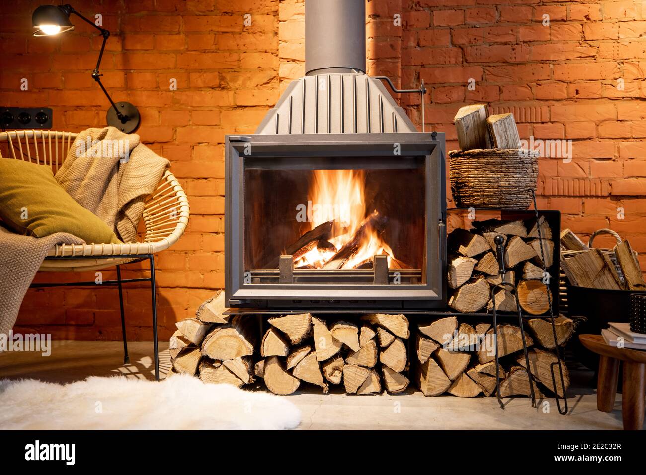 Cheminée confortable avec bois de chauffage dans la maison de style loft avec arrière-plan de mur de briques, feu de cheminée dans la cheminée, agrément de la maison en hiver Banque D'Images