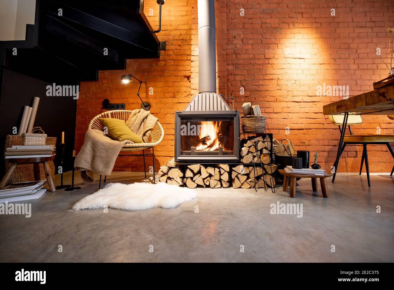 Cheminée confortable avec bois de chauffage dans la maison de style loft  avec arrière-plan de mur de briques, feu de cheminée dans la cheminée,  agrément de la maison en hiver Photo Stock -
