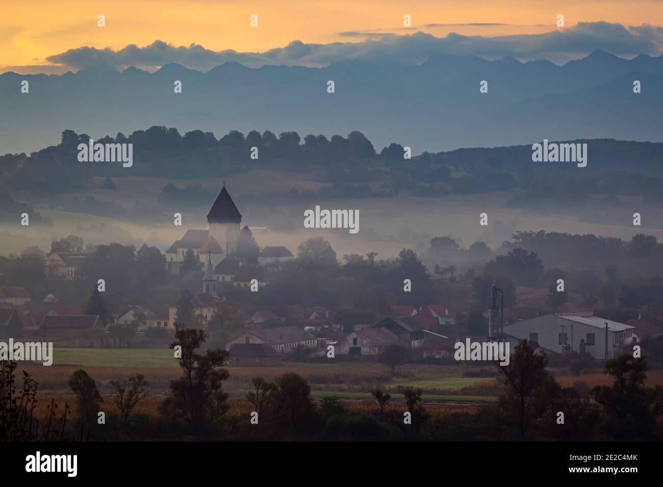 L'église fortifiée d'Hosman au lever du soleil sous une épaisse couche de brouillard et de fumée. Photo prise le 3 octobre 2020 près de Hosman, région de Transylvanie, R Banque D'Images