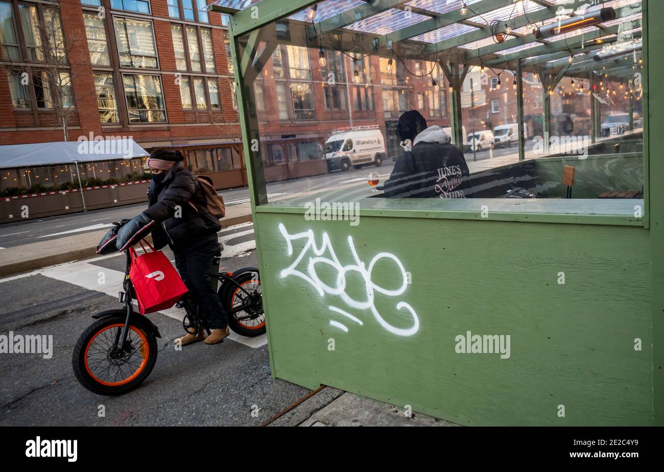 Un liveur avec un fourre-tout de marque Doordash sur son vélo à côté d'une structure de repas en plein air dans le quartier de Chelsea, à New York, le mercredi 6 janvier 2021. (© Richard B. Levine) Banque D'Images