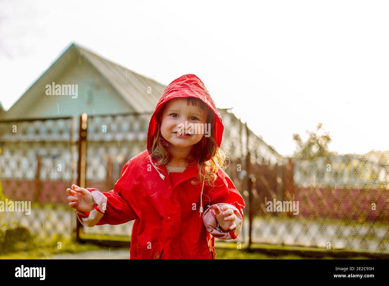 Jolie fille dans une veste rouge saute dans la flaque.le cadre chaud été ou  soleil d'automne. Été dans le village Photo Stock - Alamy