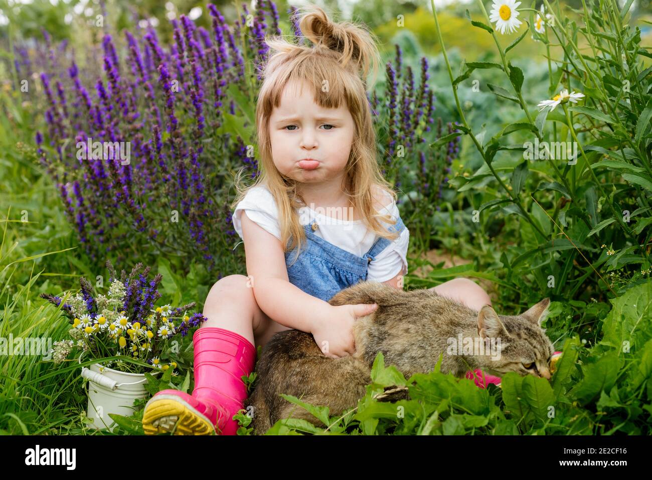 Petit enfant heureux avec chat. Fille jouant avec un animal de compagnie à l'extérieur sur le jardin. Nature estivale Banque D'Images