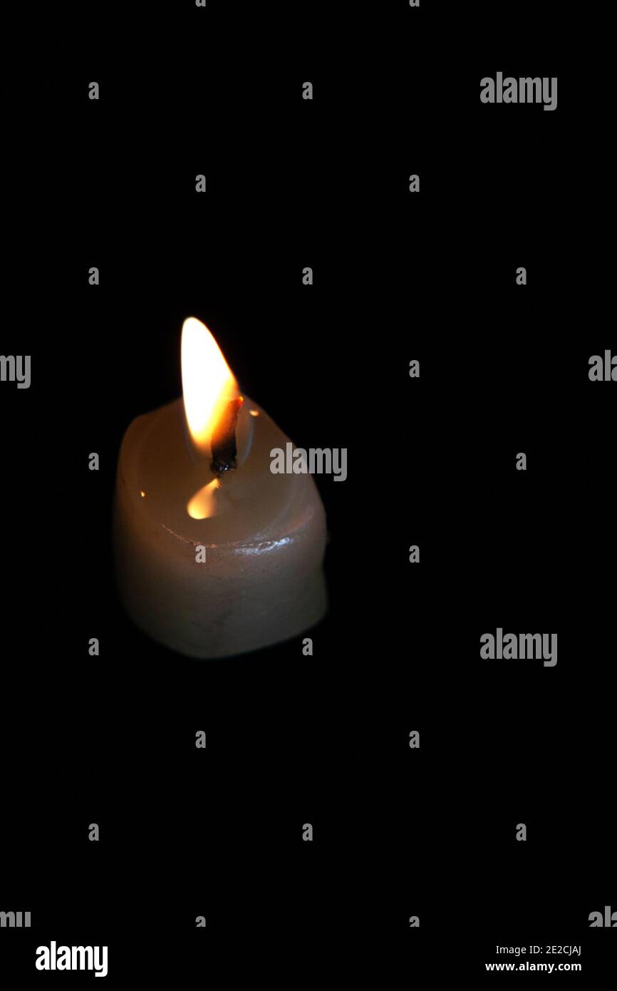 Light candle burning brillamment dans l'arrière-plan noir Banque D'Images