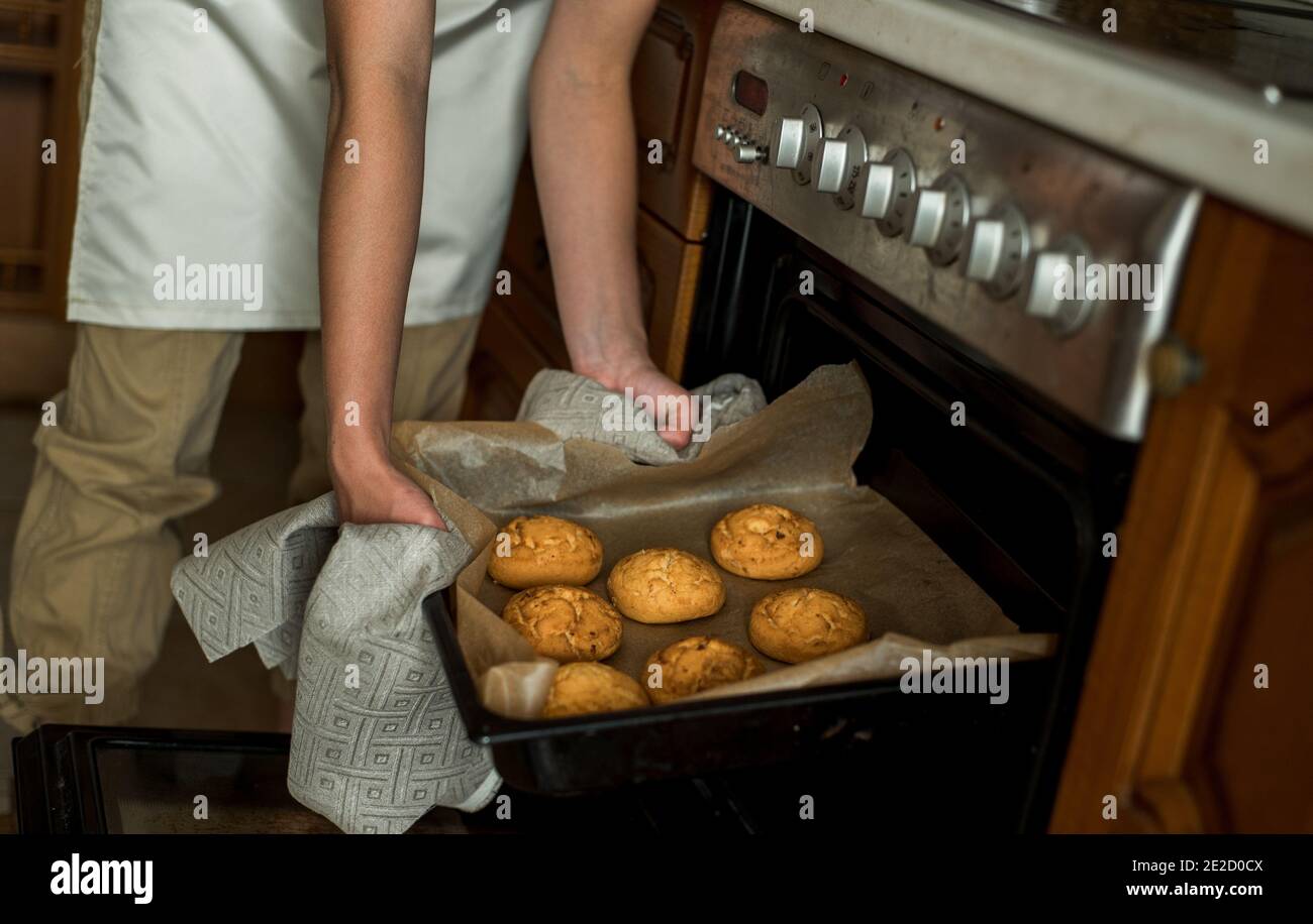 Une jeune fille souriante prend des biscuits au four. Gâteaux faits maison, biscuits et biscuits au pain d'épice. Petit déjeuner sucré dans la cuisine. Banque D'Images