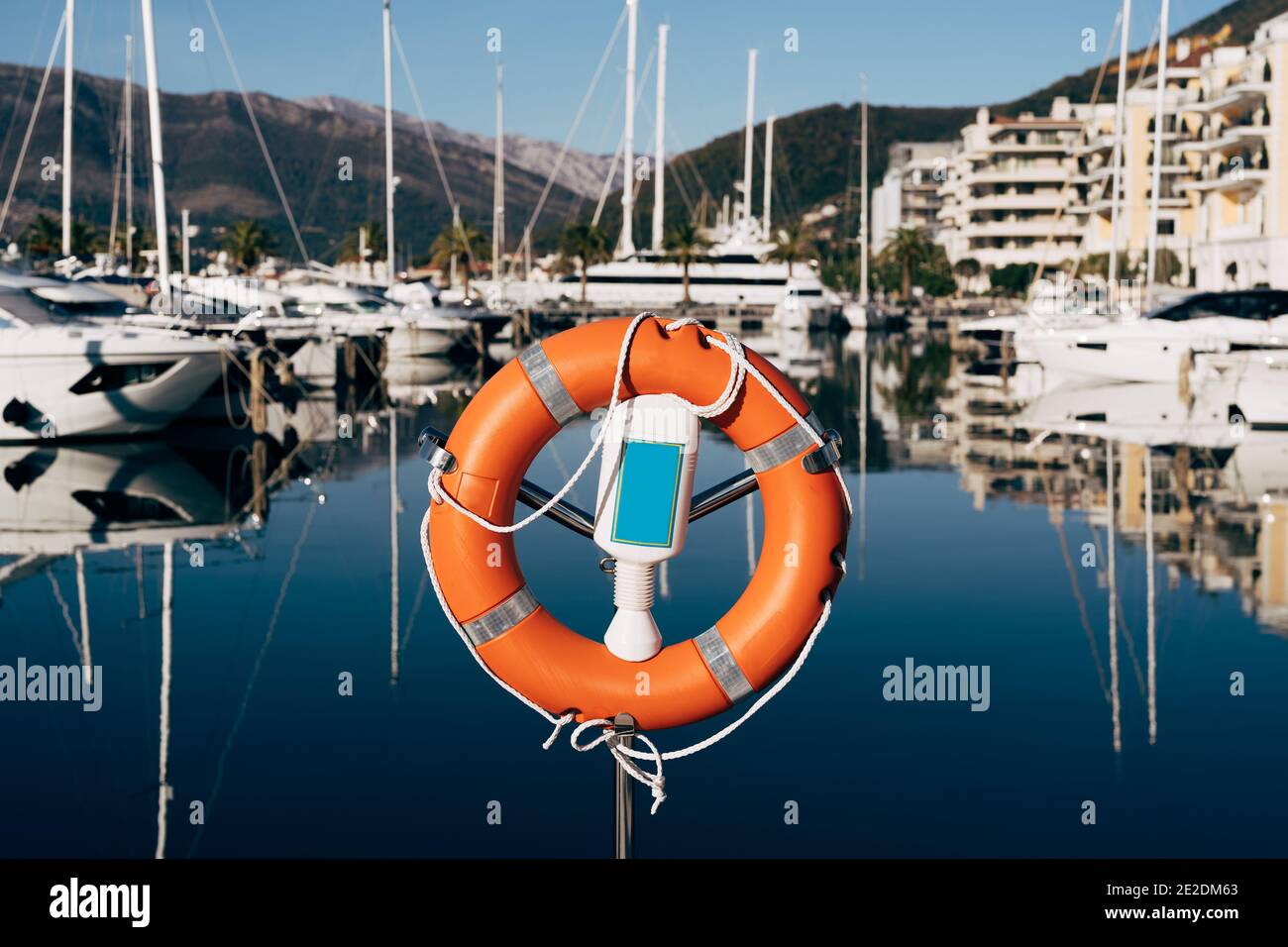 Un gros plan d'une bouée de sauvetage sur un stand sur le quai surplombant les montagnes et les yachts sur l'eau. Port de plaisance pour les yachts au Monténégro, à Tivat, près de Banque D'Images