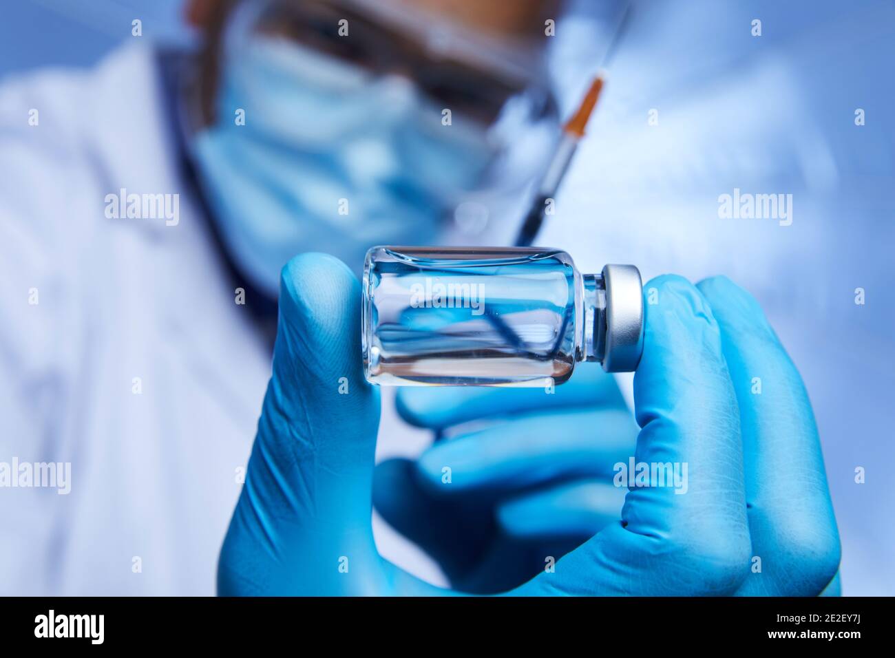 Gros plan d'un scientifique afro-américain interagissant avec une seringue et un flacon en verre de vaccin liquide en laboratoire. Banque D'Images