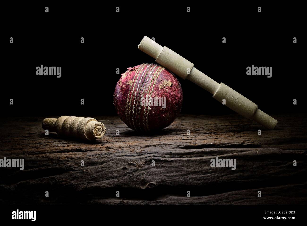 Le ballon de cricket et les lickets restent en gros plan sur une surface en bois très texturée. Stock Banque D'Images