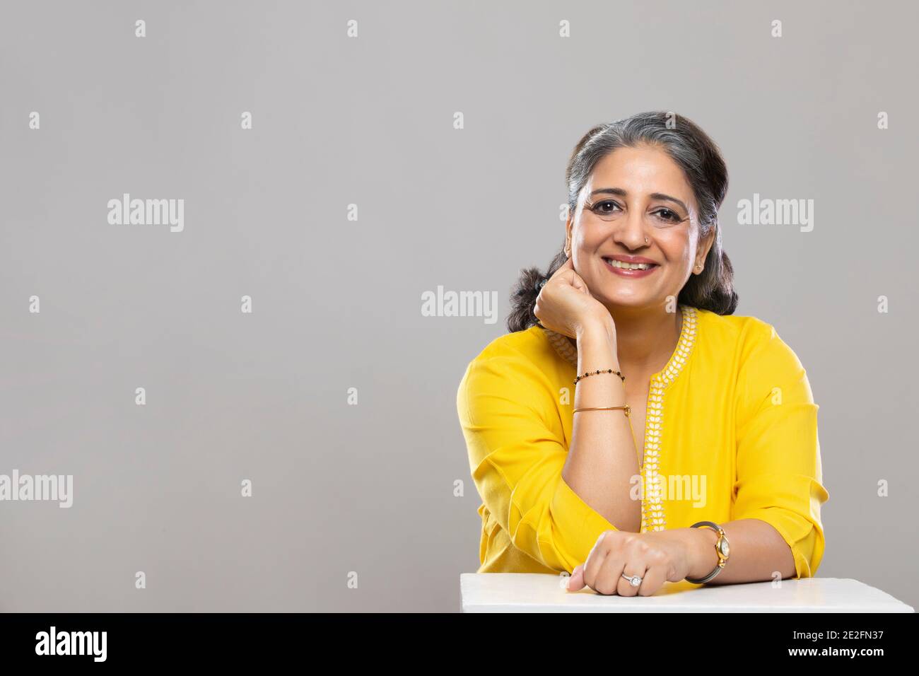 UNE FEMME ADULTE ÂGÉE ASSISE ET SOURIANT À LA CAMÉRA Banque D'Images