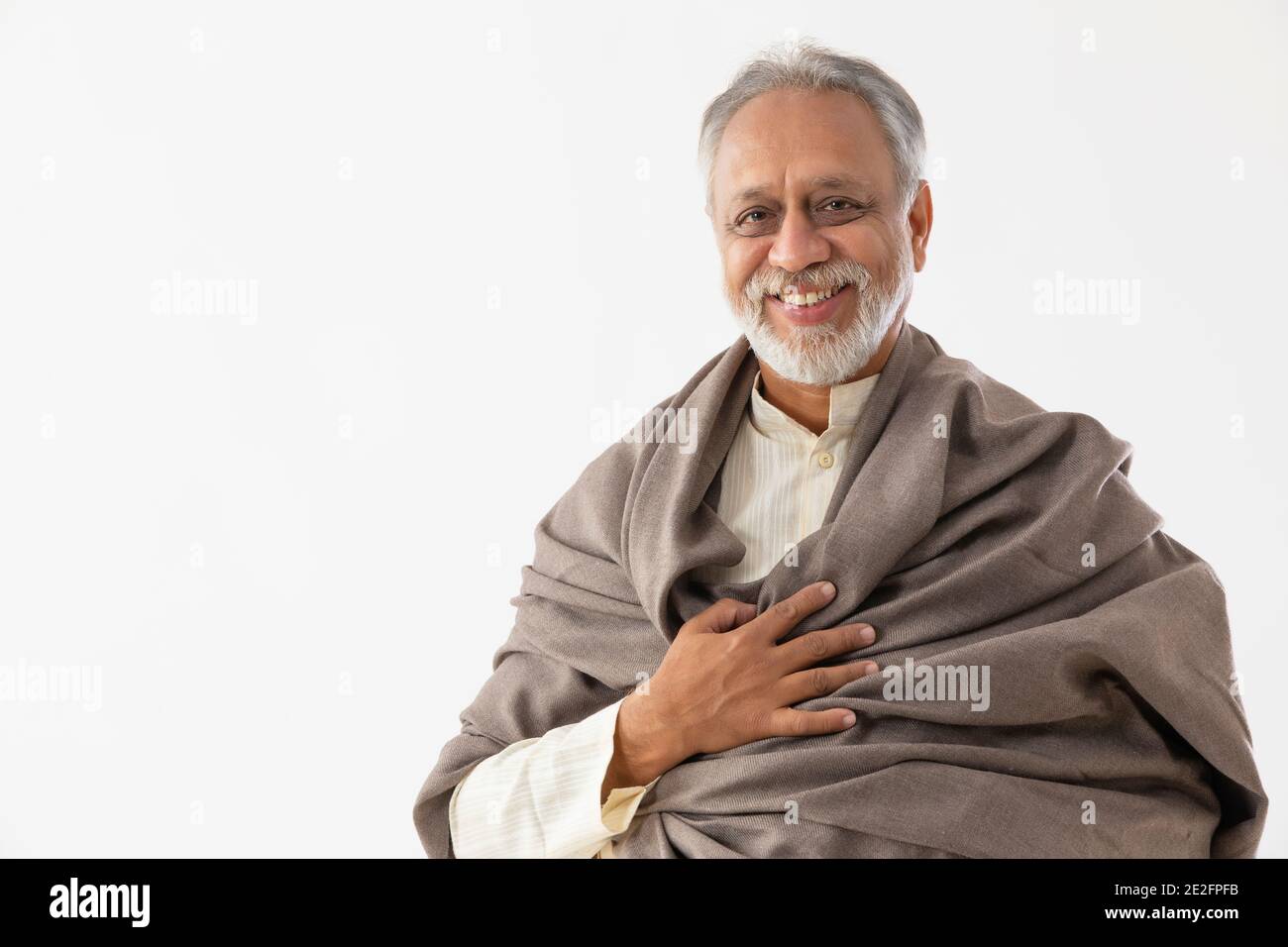 UN VIEIL HOMME QUI PORTE LE CHÂLE SOURIANT À L'APPAREIL PHOTO Banque D'Images