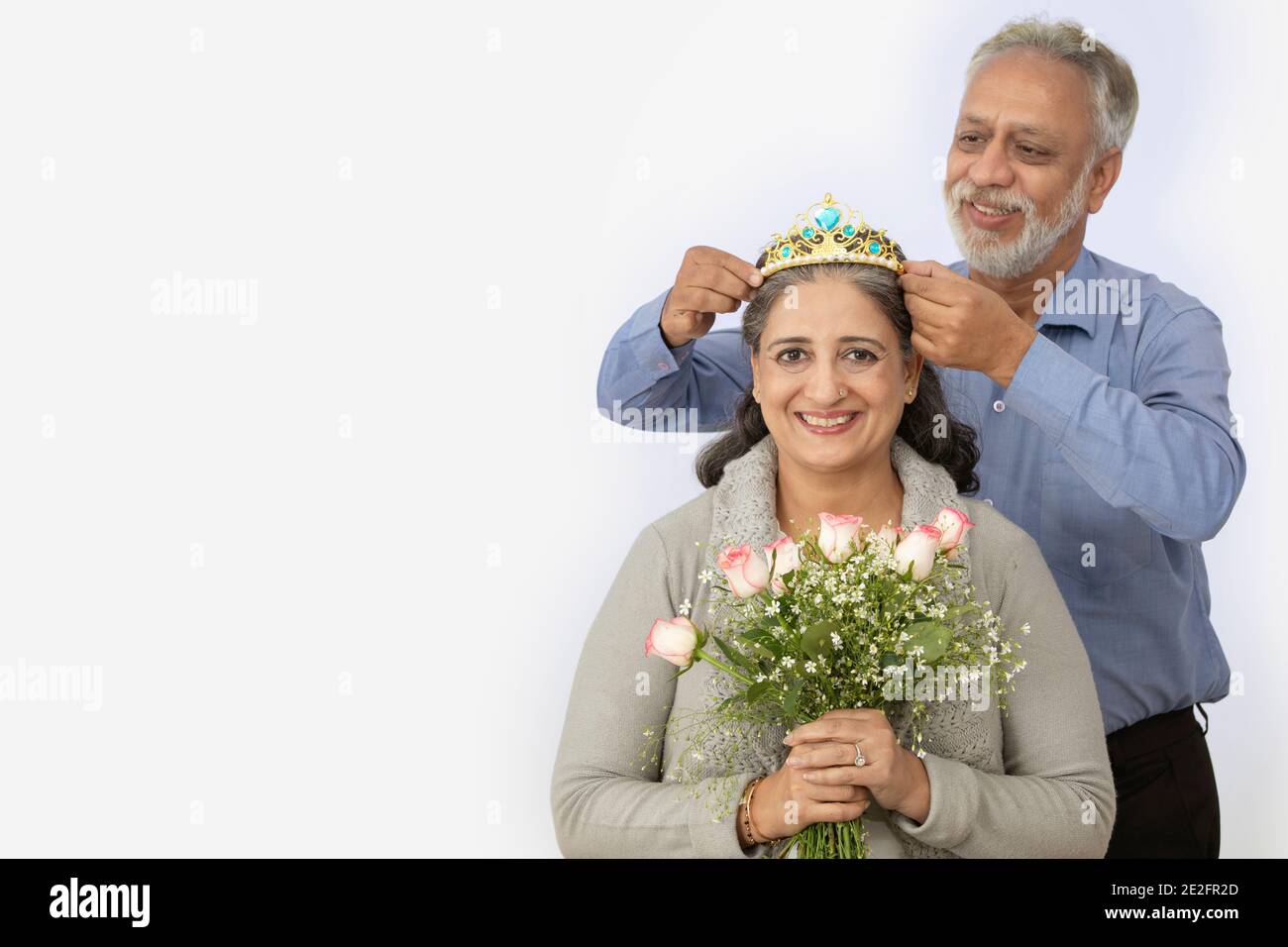UNE FEMME ADULTE SÉNIOR ASSISE AVEC SON MARI, LA COURONNANT HEUREUSEMENT Banque D'Images