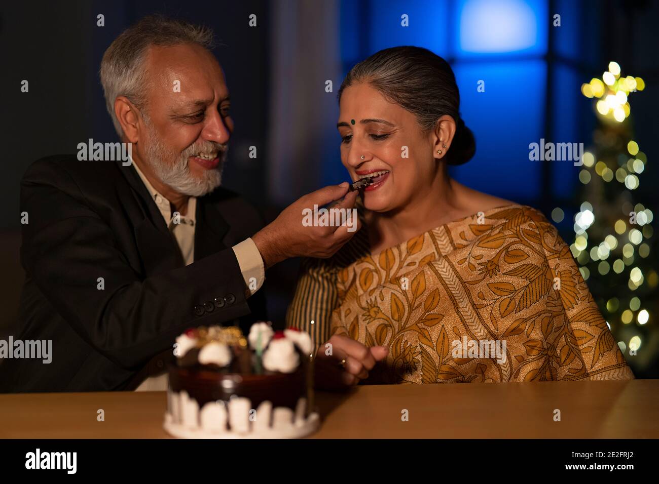 UN HOMME ADULTE SENIOR QUI DONNE UN GÂTEAU À SA FEMME PENDANT SON ANNIVERSAIRE CÉLÉBRATIONS Banque D'Images