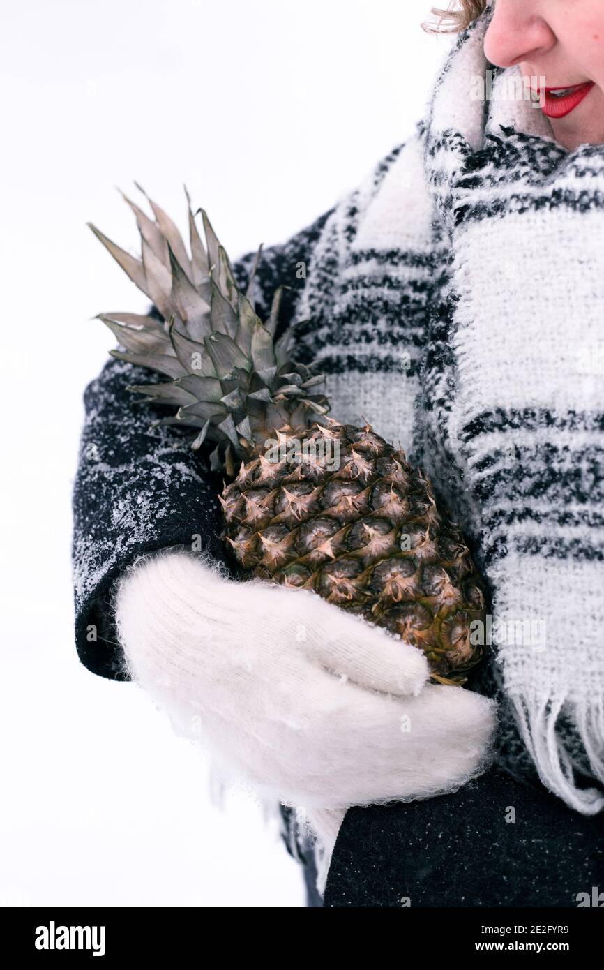 Une fille en moufles tient l'ananas en hiver Banque D'Images