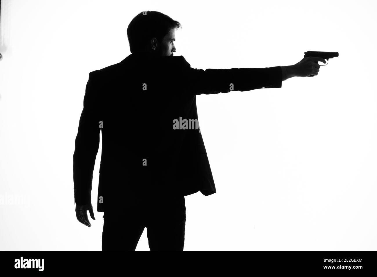 ombre d'un homme avec un pistolet dans ses mains viser le bruit de fond de la lumière du crime détective Banque D'Images