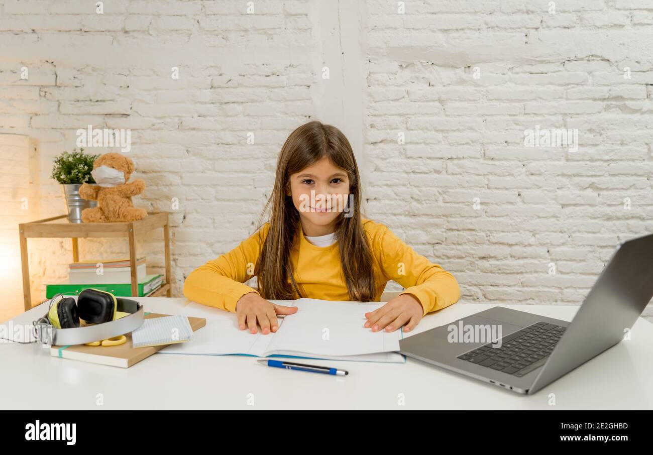 Bonne écolière sur ordinateur portable étudiant en ligne dans une télécommande virtuelle cours sur internet à la maison car les écoles restent fermées en raison du dernier lockdo du coronavirus Banque D'Images