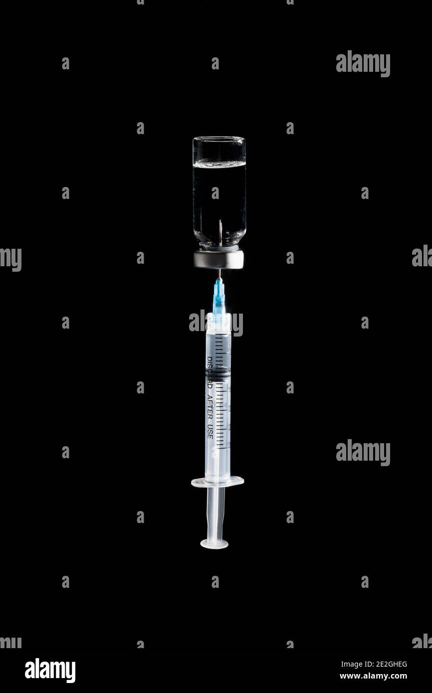 Seringue dans un flacon de vaccin COVID-19 sur fond noir Banque D'Images