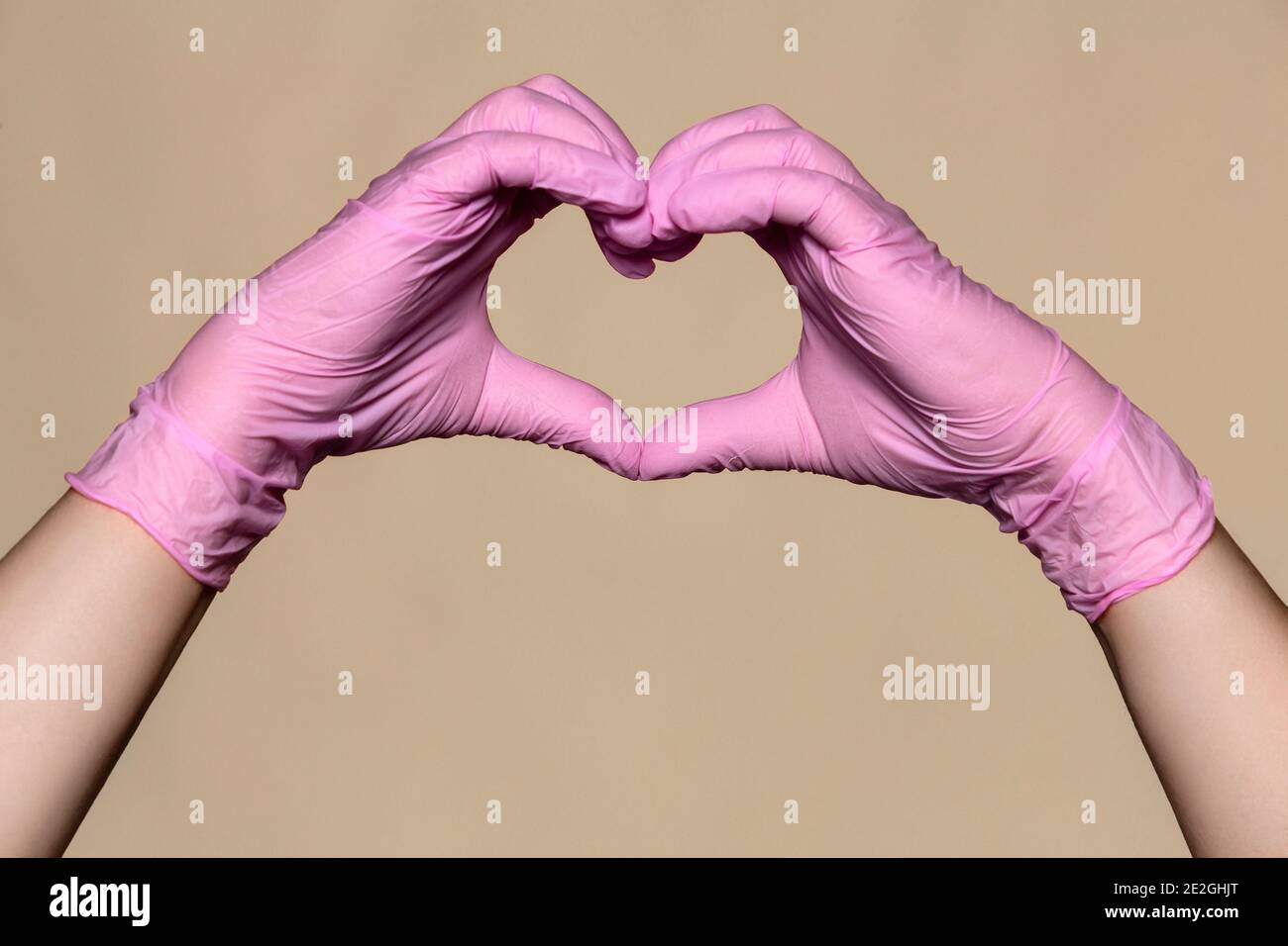Mains en gants de protection roses formant la forme du cœur Banque D'Images