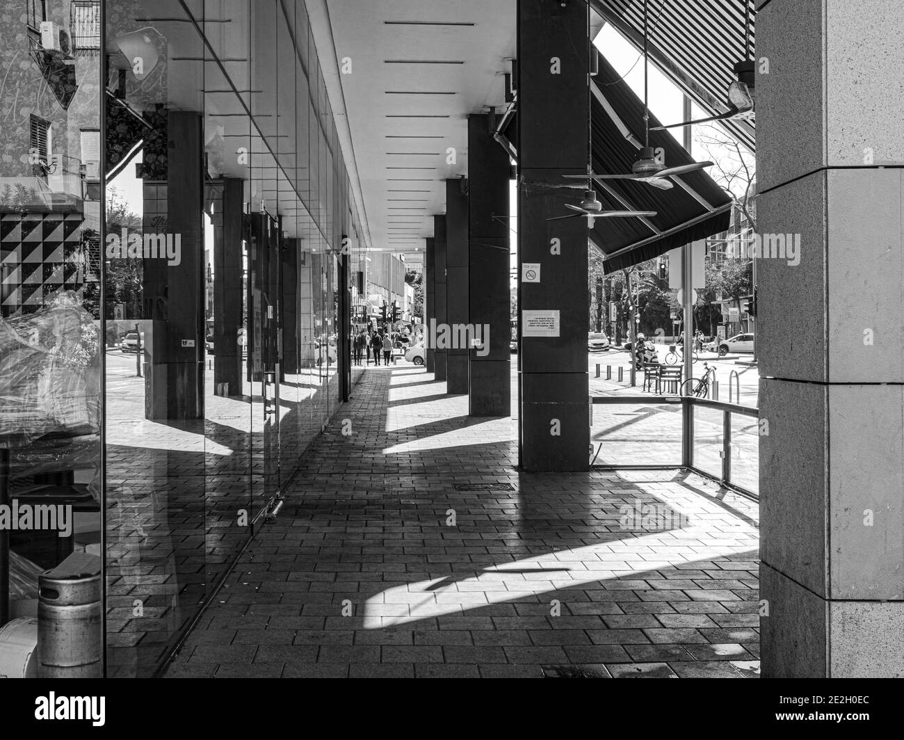 image en noir et blanc avec vue sur la chaussée avec parasol et colonnade le long des magasins Banque D'Images