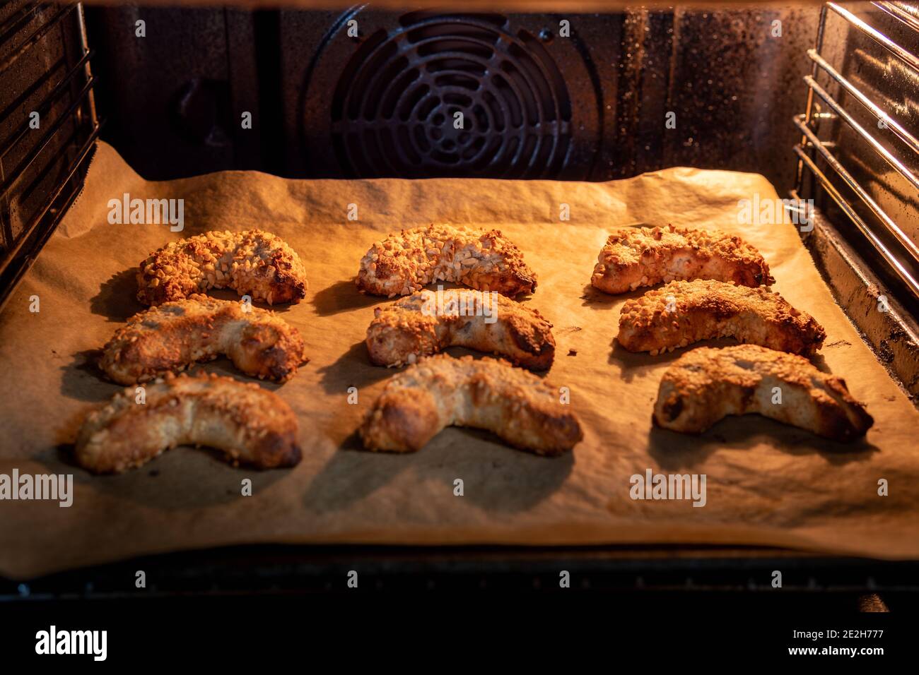 Délicieux et croustillant croissants d'amande végétalienne avec amandes hachées sur une plaque de cuisson dans un four éclairé. C'est une savoureuse pâtisserie macaron avec du massepain. Banque D'Images