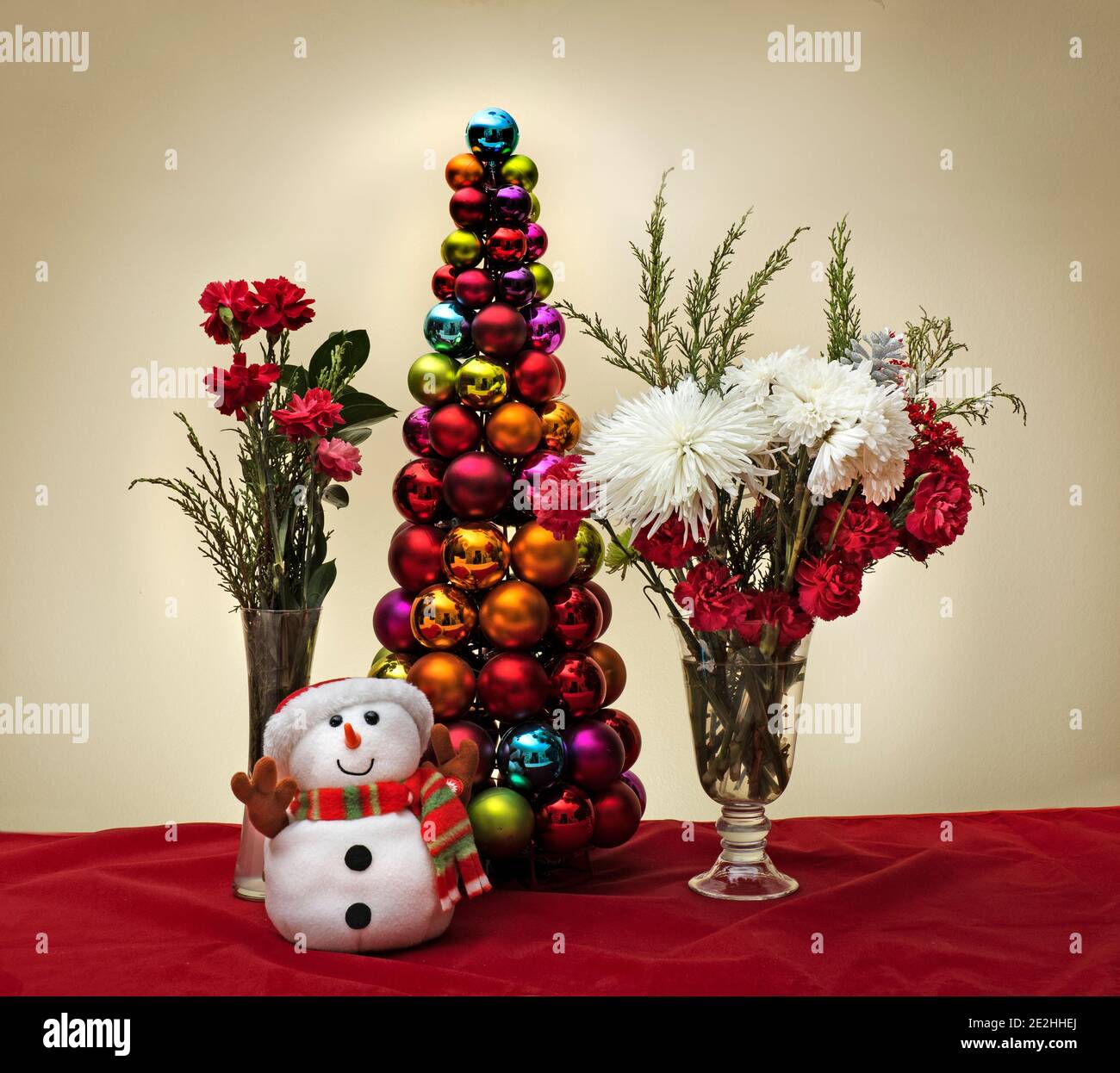 Scène de Noël avec fleurs bonhomme de neige et arbre de noël fait de boules décoratives brillantes Banque D'Images