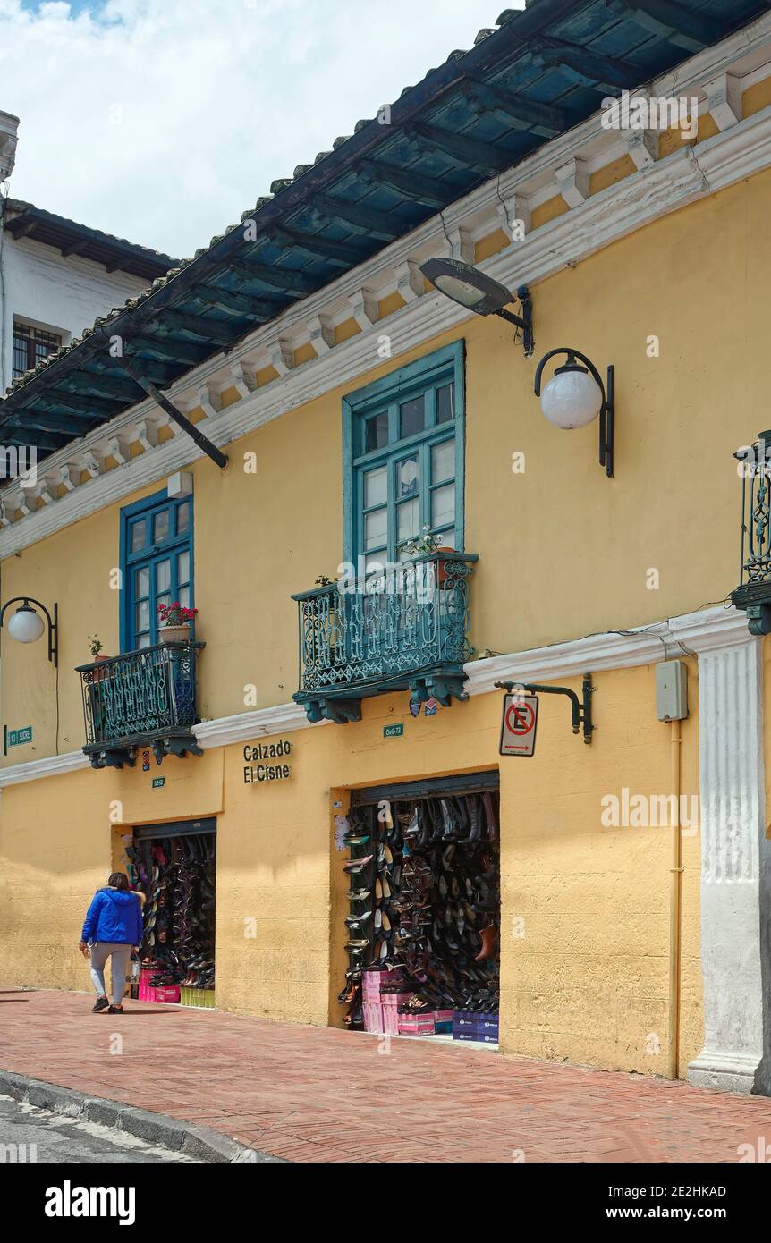 Vieux bâtiment jaune, magasins de chaussures, magasins, entreprises, balcons en fer, trottoir en brique, femme marchant, scène de la ville; Amérique du Sud; Quito, Equateur Banque D'Images