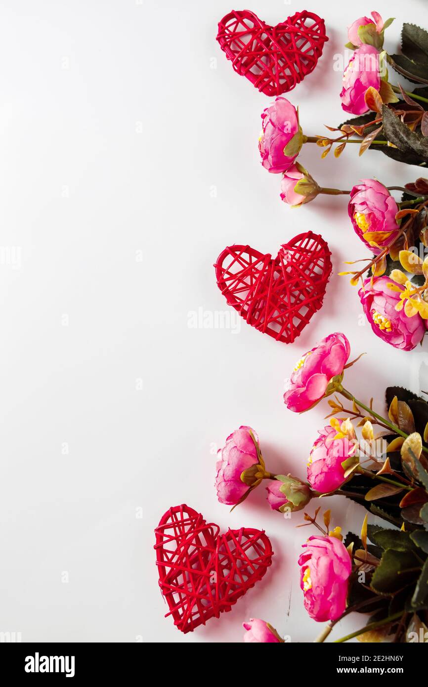 Cadre vertical pour la Saint Valentin, coeurs rouges et fleurs roses sur fond blanc. Banque D'Images