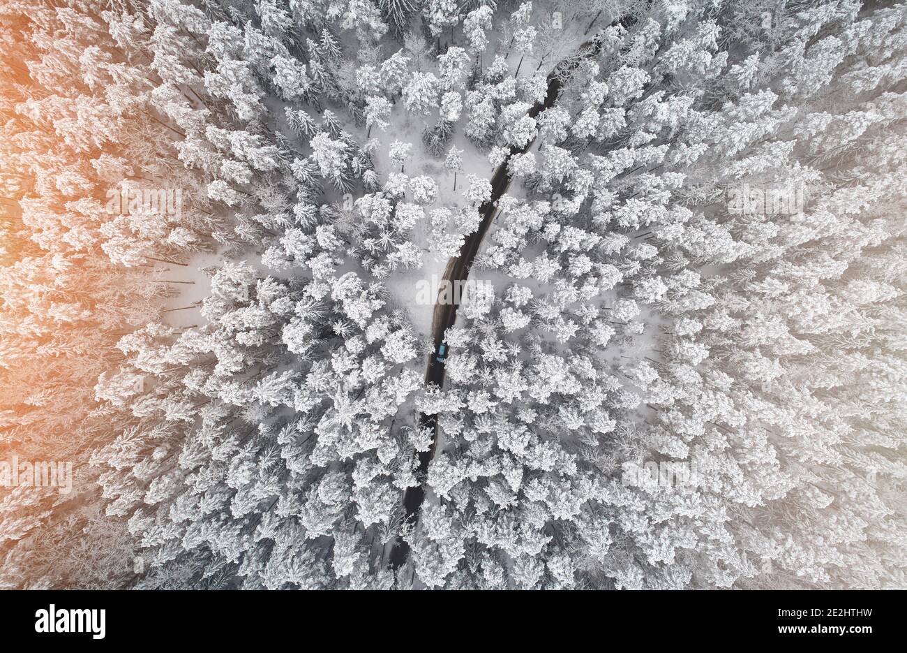 La voiture se déplace sur la route autour de la forêt d'hiver au-dessus de haut drone vue Banque D'Images