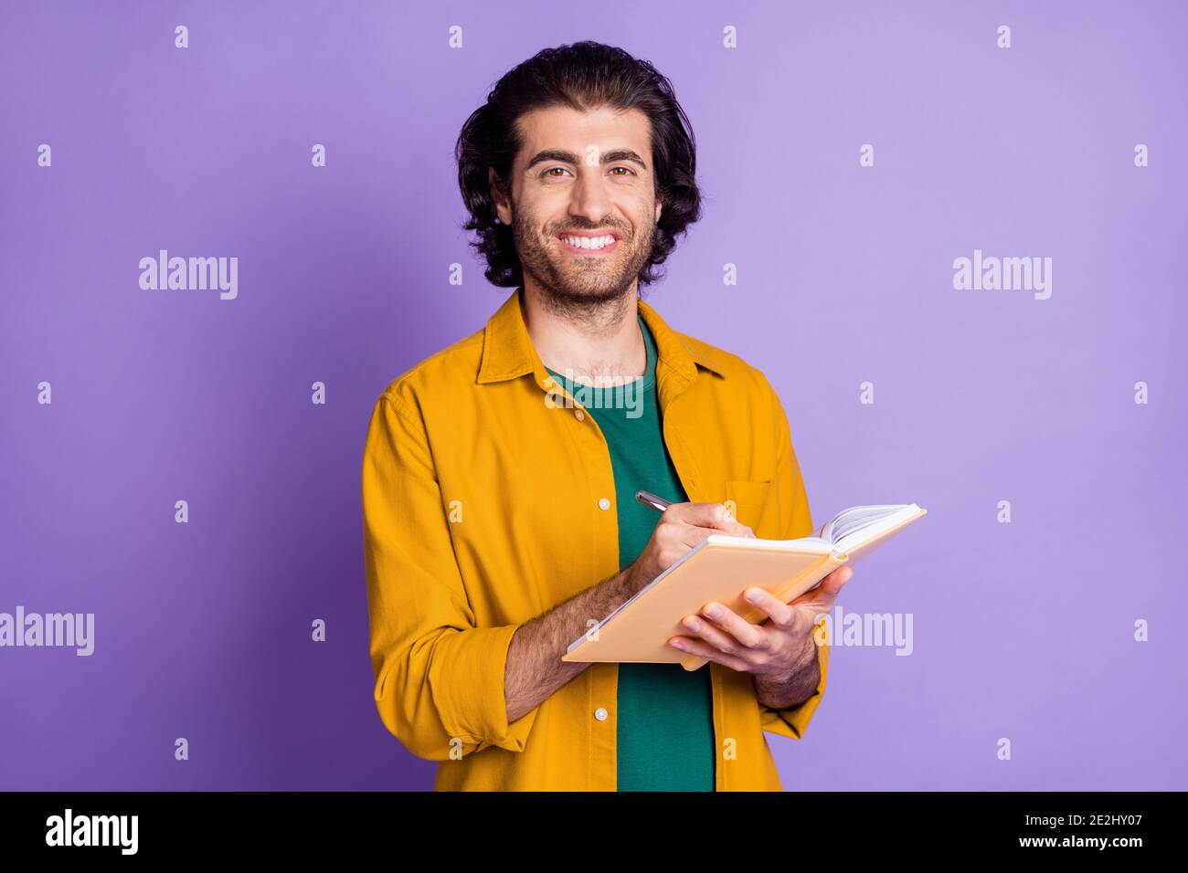Photo de gai jeune homme de chaume heureux positif sourire écrire liste des tâches bloc-notes isolé sur fond violet Banque D'Images
