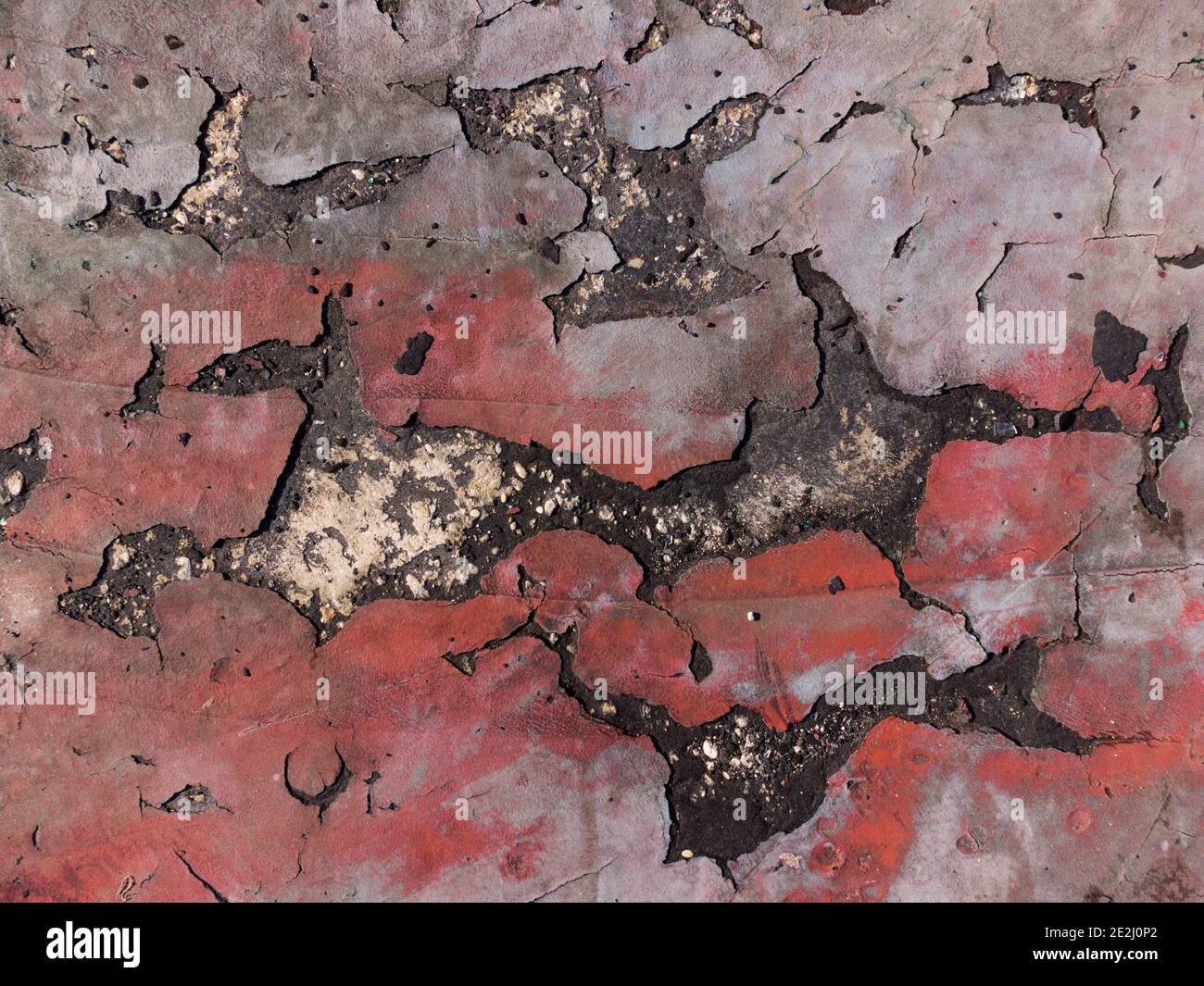 Fissures sur une ancienne texture de sol rouge en béton éraflée fond d'écran Banque D'Images