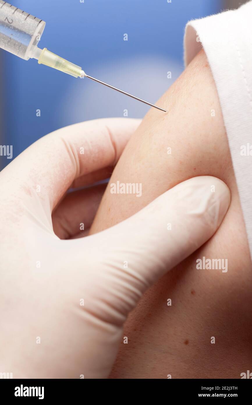 Gros plan de la vaccination contre le covid-19 avec une seringue dans le haut du bras - focus sur l'aiguille Banque D'Images
