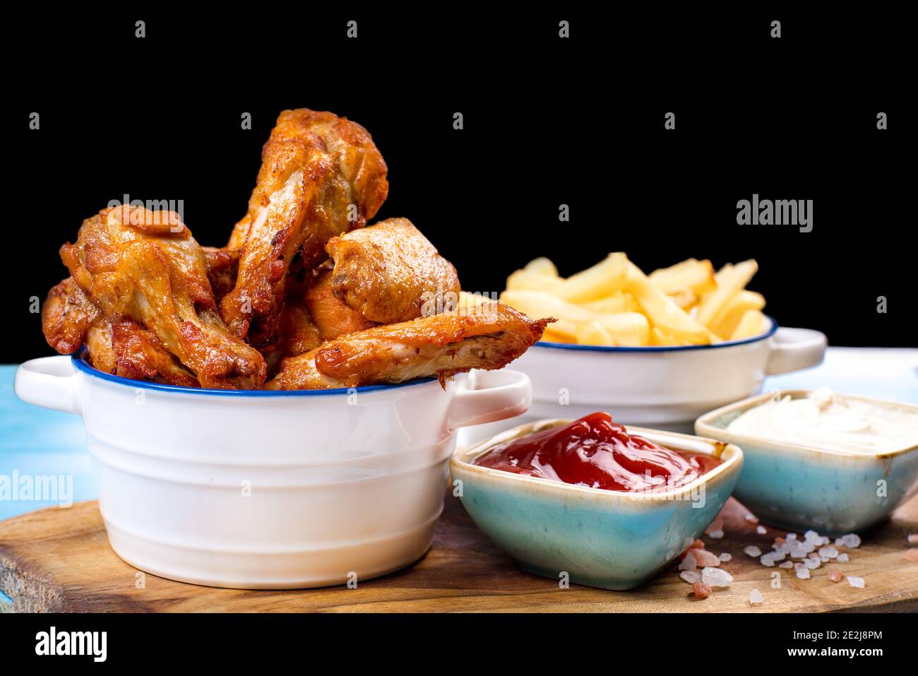 Beignets de poulet frits dans un seau avec sauce sur fond bleu. Poulet bandes panées dans de petits pots en céramique avec ketchup et blanc Sauce avec mousse précuite Banque D'Images