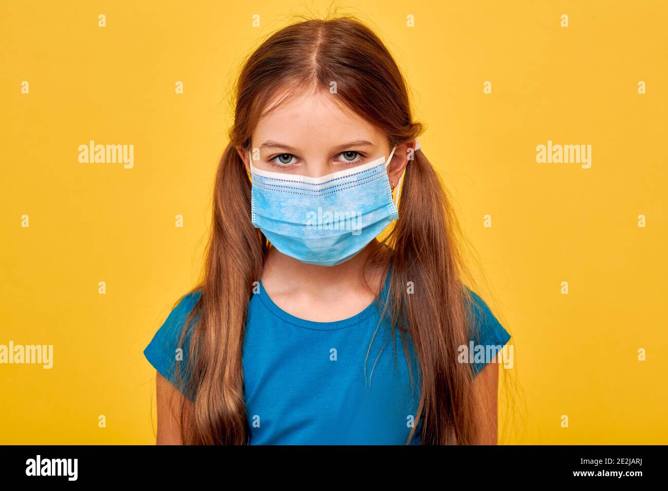 Petite fille portant dans un masque médical et des yeux très tristes parce que le coronavirus pandémique dans le monde, sur fond jaune. Protection selon COVID-19 Banque D'Images
