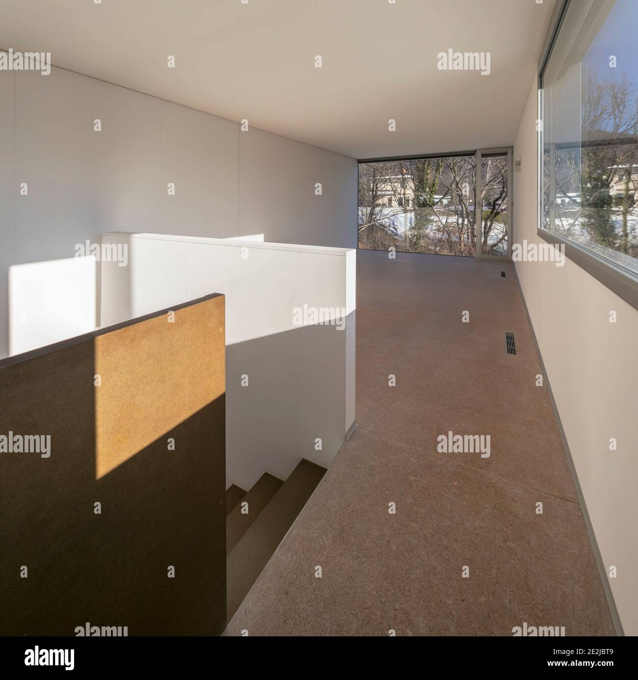 Intérieur spacieux d'un appartement vide avec de grandes fenêtres. Un escalier en bois qui vient d'en dessous Banque D'Images