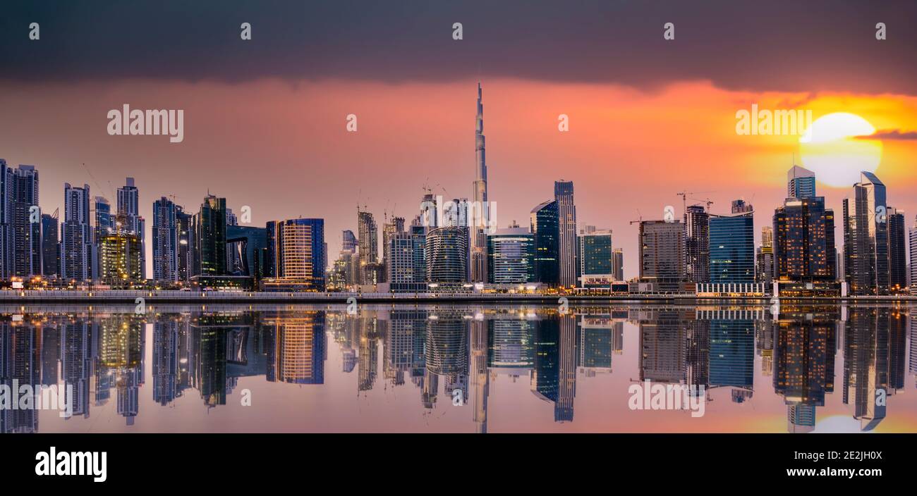 Vue panoramique sur les gratte-ciel de Dubaï au coucher du soleil avec des bâtiments et des gratte-ciels reflétés sur la rivière de Singapour qui coule en premier plan. Dubaï, Émirats arabes Unis Banque D'Images