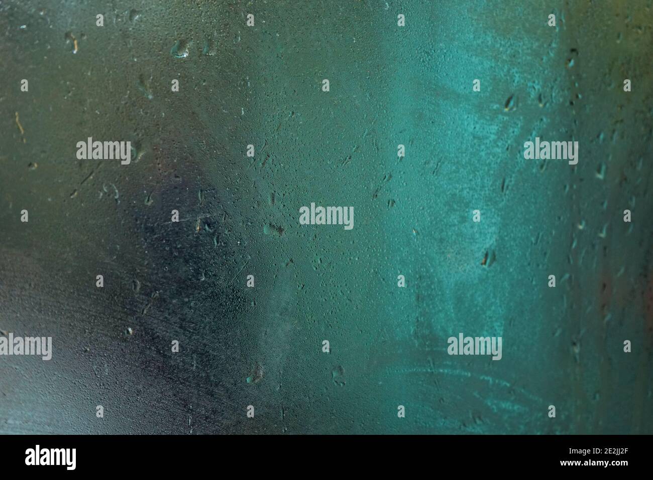 Fenêtre humide et torride à l'intérieur du bus par temps pluvieux, fond clair de néon vert flou Banque D'Images