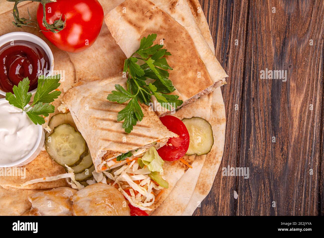 Populaire arabe turc fastfood Doner shawarma rouler avec de la viande et des légumes et des ingrédients sur fond de bois. Vue du dessus Banque D'Images