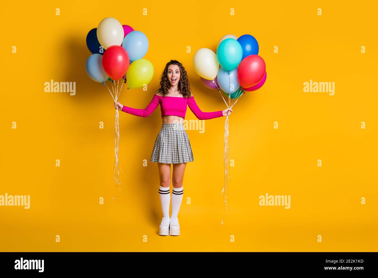 Pleine longueur photo de taille de corps de drôle surpris écolière tenue ballons d'air dans les deux mains riant gaiement avec ouvert bouche isolée Banque D'Images