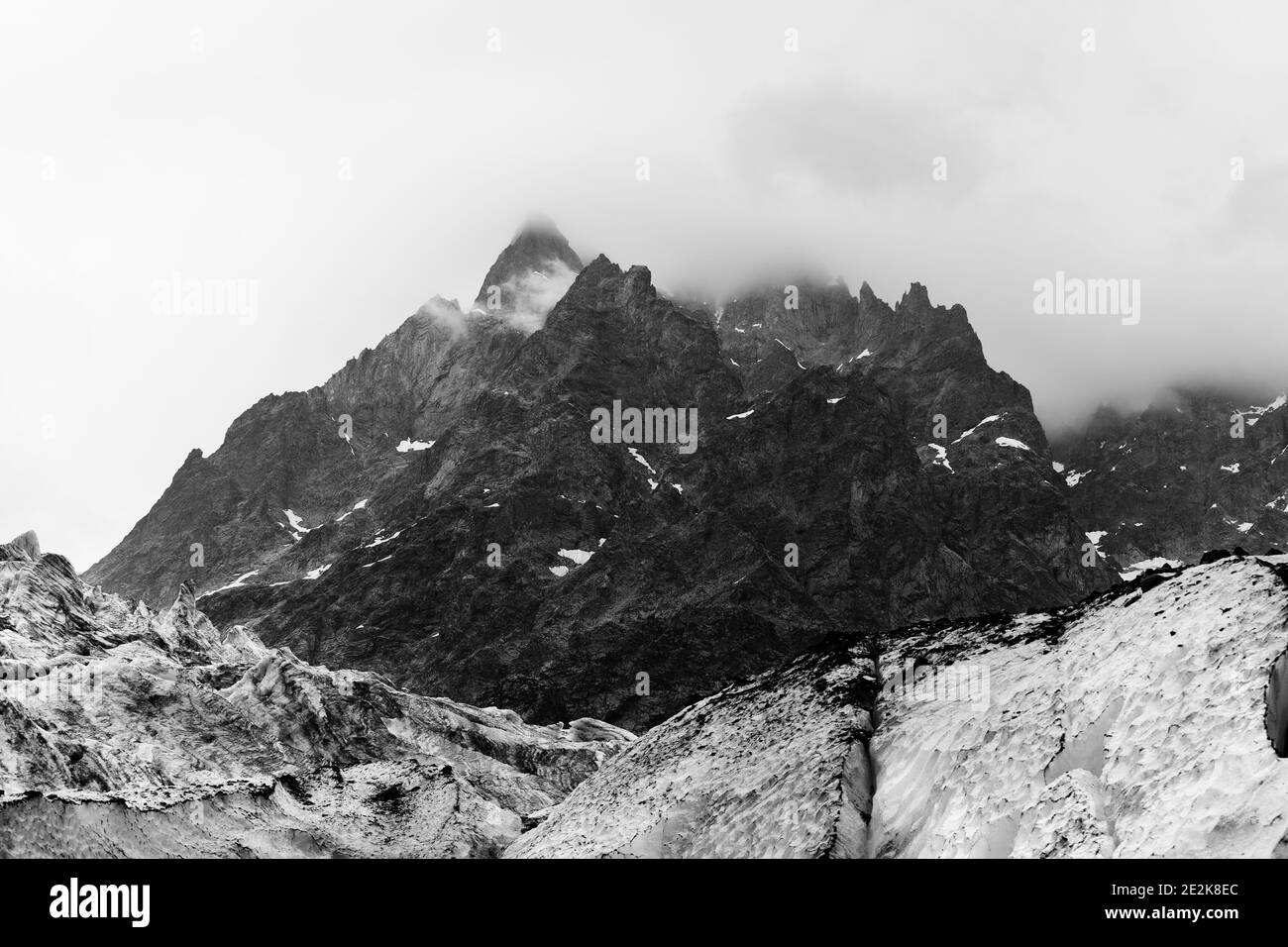 Hautes montagnes rocheuses dans le brouillard et le glacier avec des crevasses de danger profond couvertes de neige et de terre à jour gris. Montagnes du Caucase. Géorgie, région Svane Banque D'Images