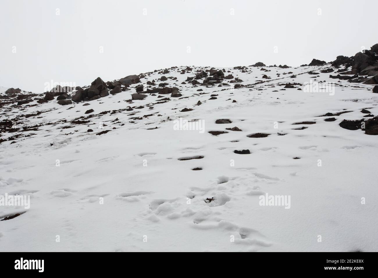 Détail d'une colline montagneuse avec neige et rochers, ciel blanc nuageux en Equateur Banque D'Images