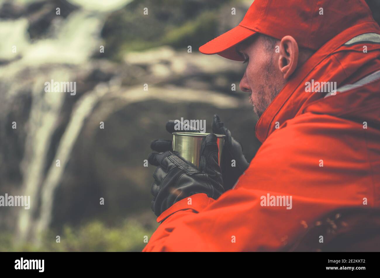 Les hommes caucasiens dans ses années 30 Drinking Hot Tea de sa coupe de métal tout en prenant une courte pause sur le Trailhead alpin. Réchauffement des randonneurs. Banque D'Images