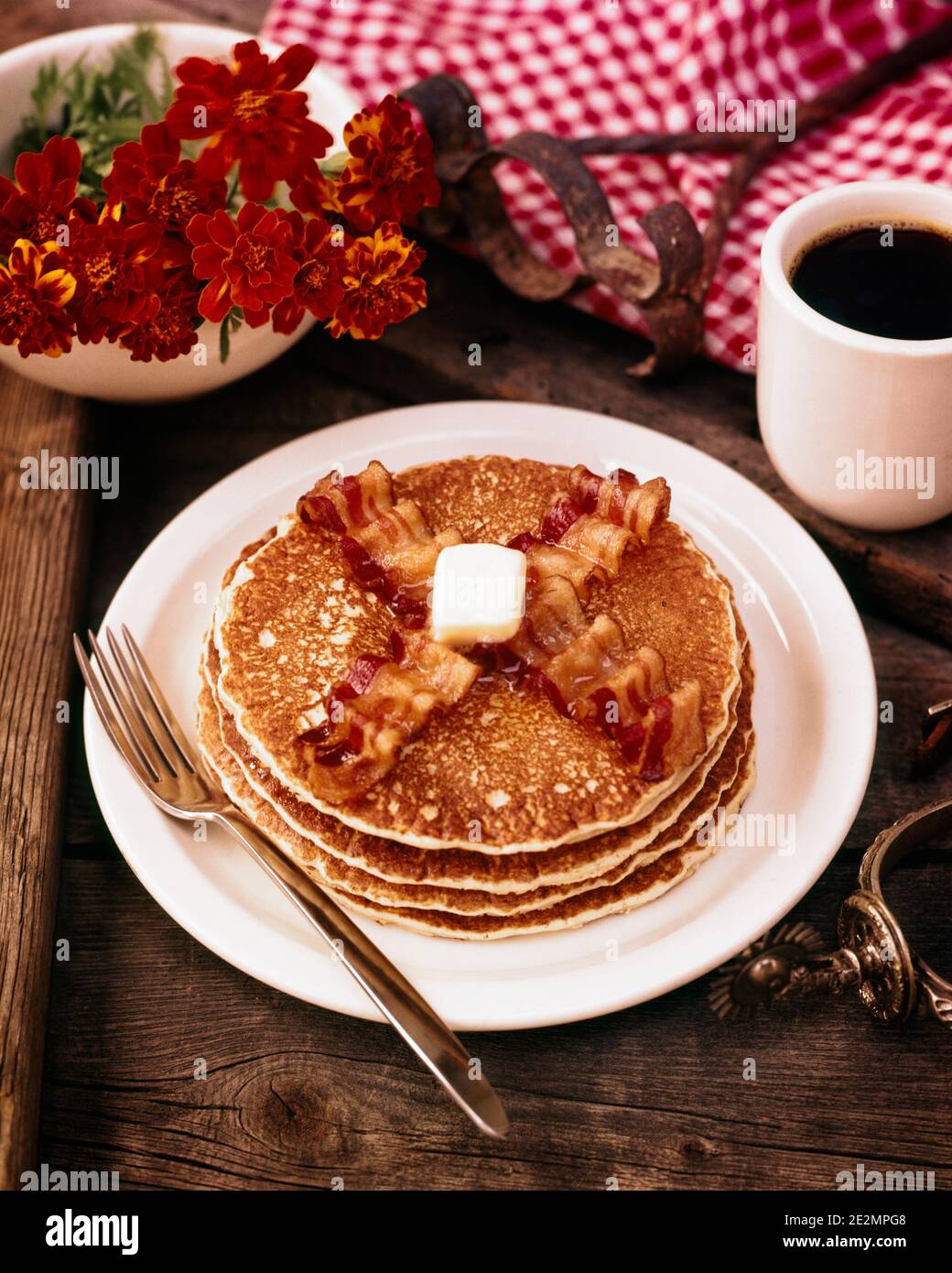 LES ANNÉES 70 PETIT DÉJEUNER PILE DE QUATRE CRÊPES DE FARINE DEUX BANDES DE BEURRE DE BACON UNE TASSE DE CAFÉ NOIR FLEURS WESTERN BOTTE ÉPERON - KF4442 HAR001 HARS CONCEPTUEL ENCORE VIE ÉLÉGANT ÉPERON MARQUE MARIGOLDS FLAPJACKS GRIDDLE GÂTEAUX HAR001 OLD FASHIONED Banque D'Images